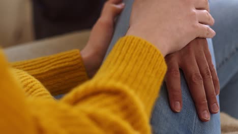 Black-man-hand-touch-woman-leg-with-jeans-at-home,-close-up