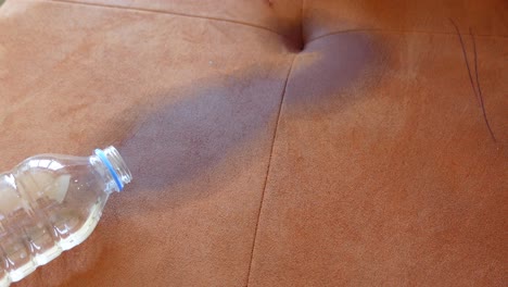 water bottle spilled on a brown couch