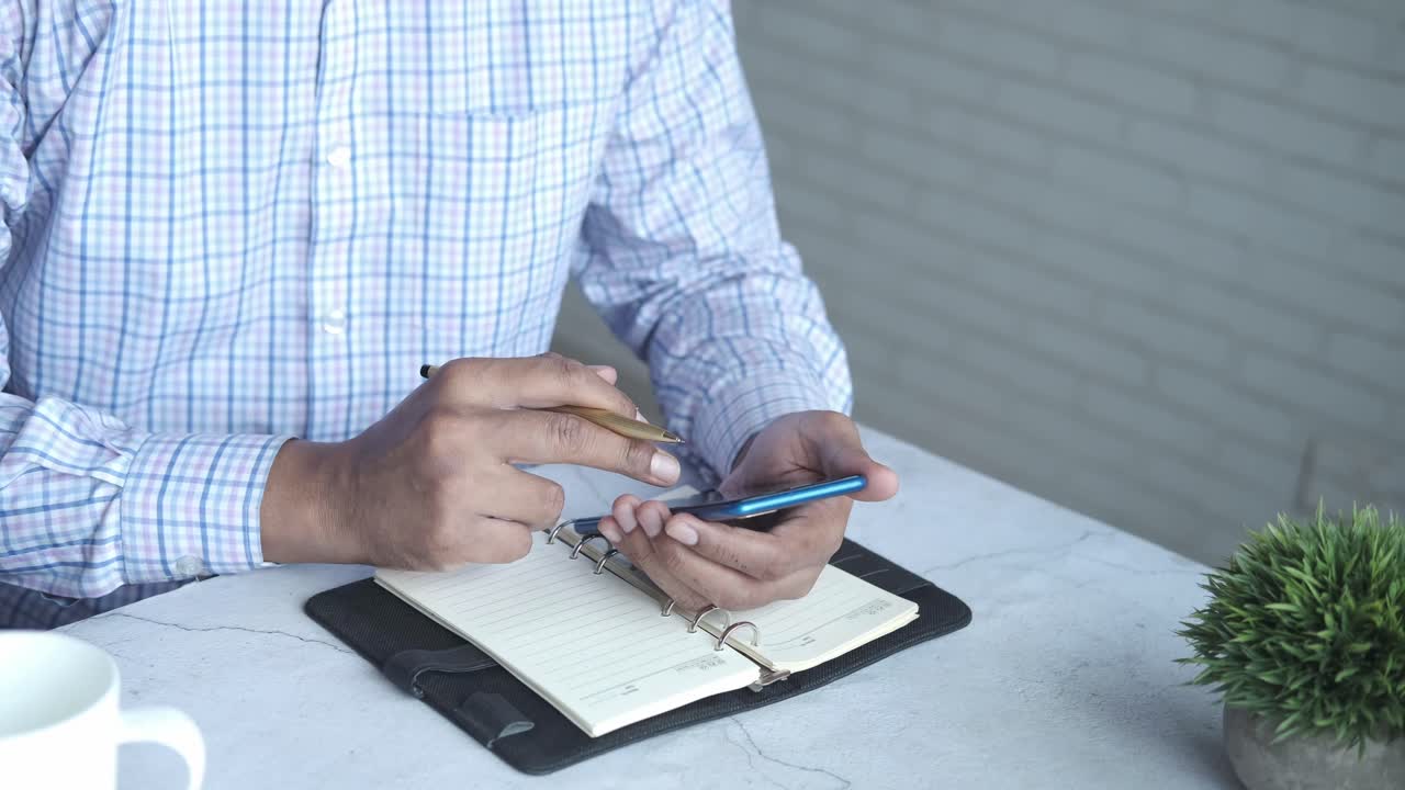 Businessman Checking Phone and Taking Notes