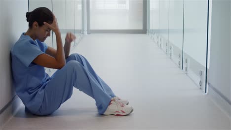 sad female surgeon sitting in corridor