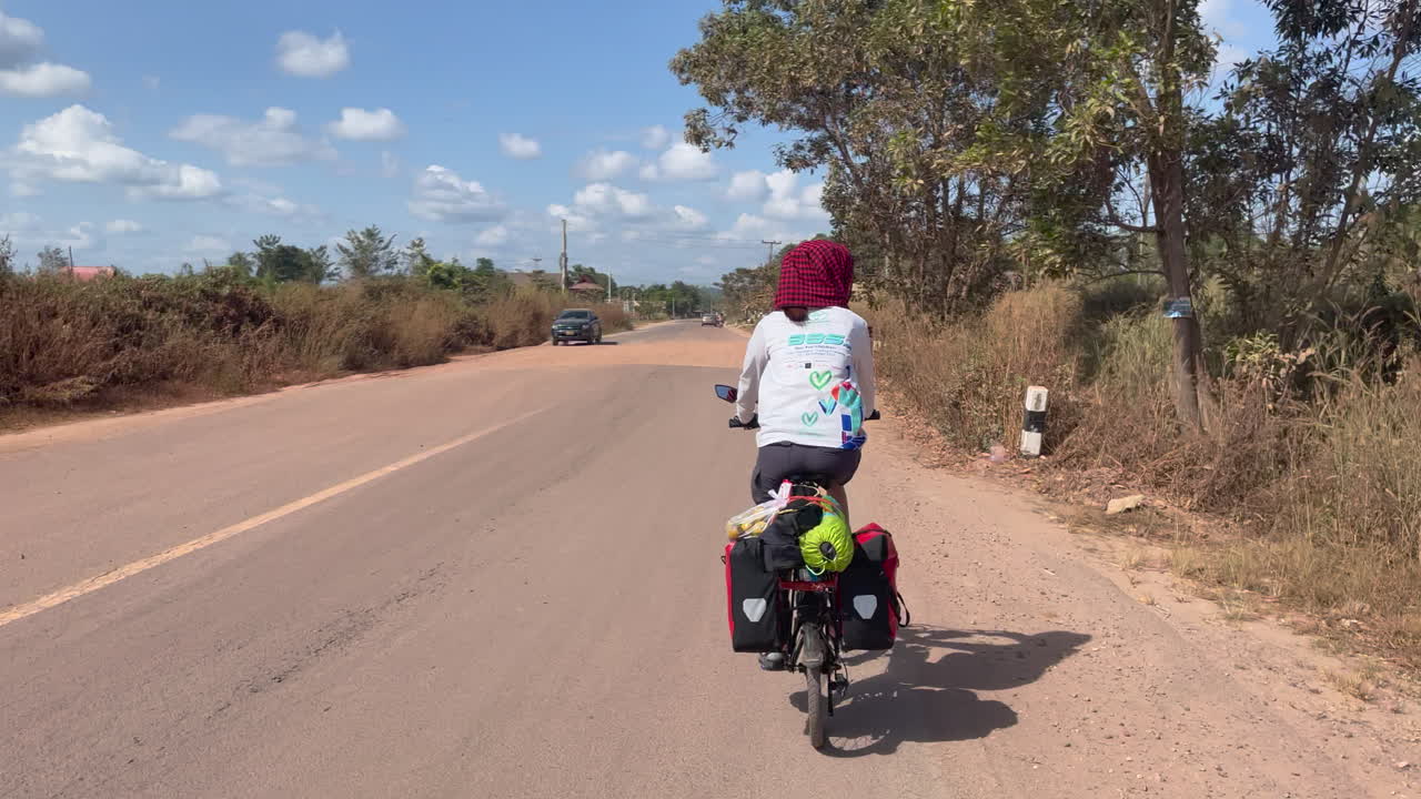 Ripresa da dietro di donne in bicicletta su una strada nella giungla in Laos.