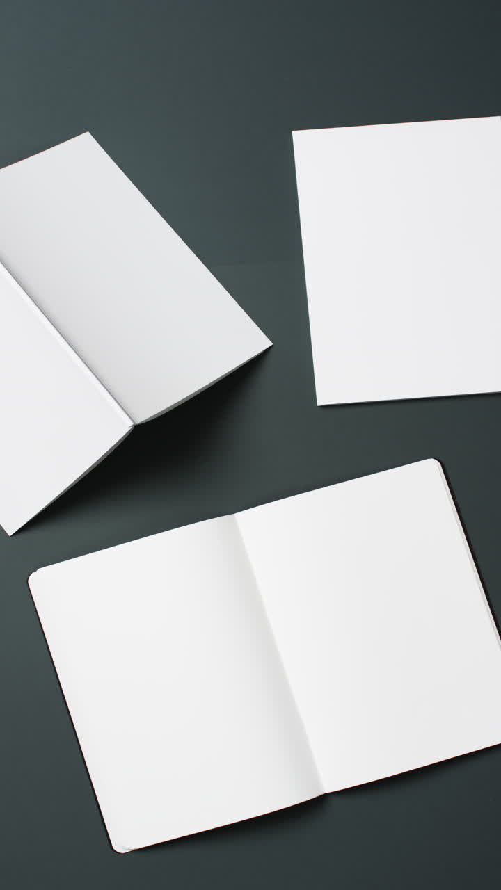 Vertical video of books with white blank pages and copy space on black background