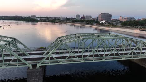 cars on campus bridge over delaware river at dawn sunrise in america. trenton cityscapein background. aerial rising wide shot. famous morrisville trenton bridge