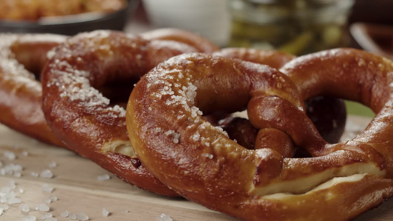 Käsi asettaa vastaleivottuja, suolaisia pehmeitä pretzeleitä.