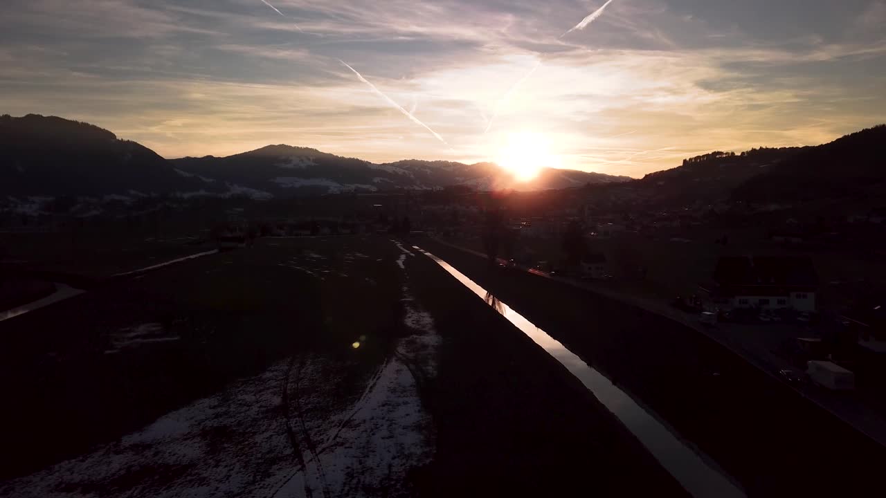 일몰 동안 반사되는 강, 자동차, 마을이 있는 스위스의 아름답고 변덕스러운 겨울 원더랜드 풍경