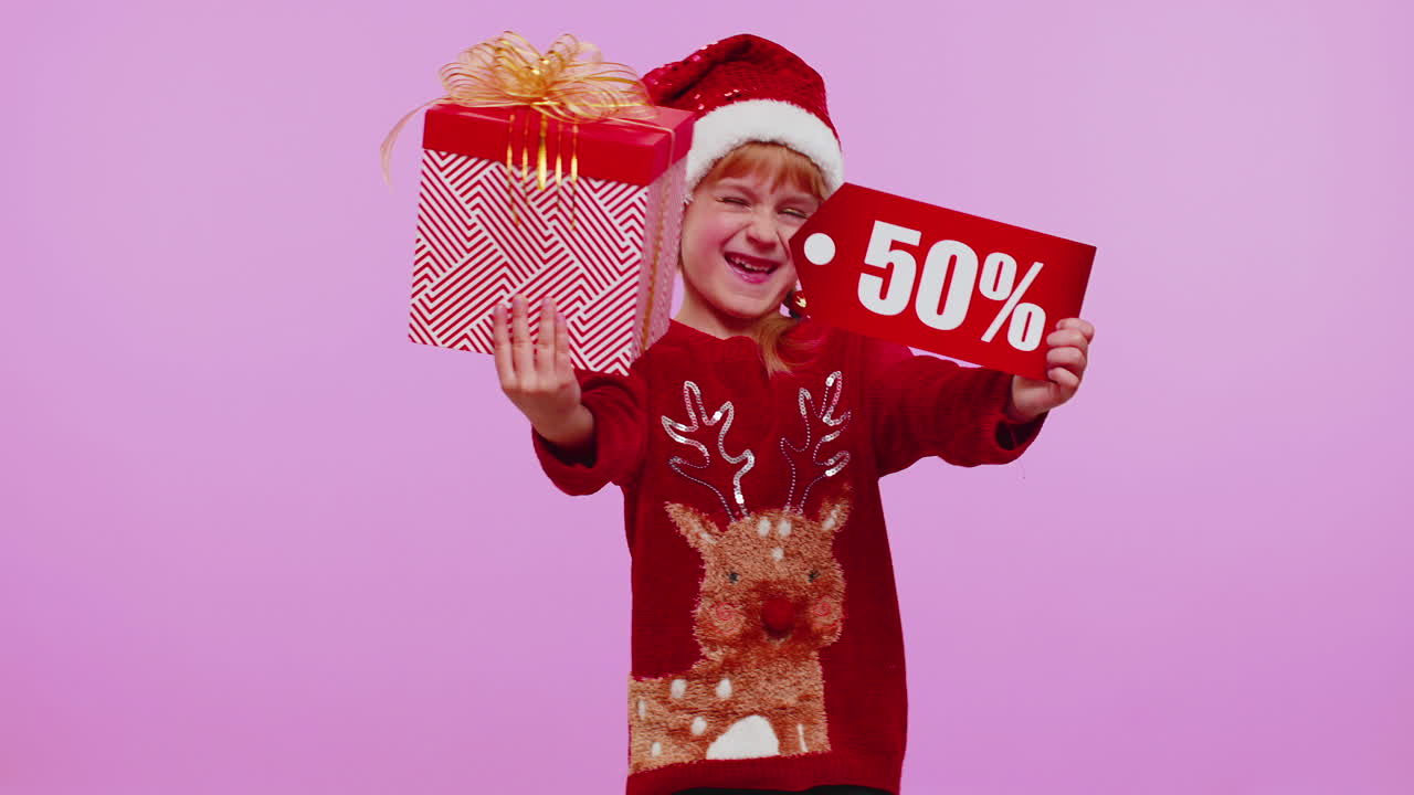 niña con sombrero de navidad mostrando caja de regalos y inscripciones de descuento del 50 por ciento nota de texto de banner