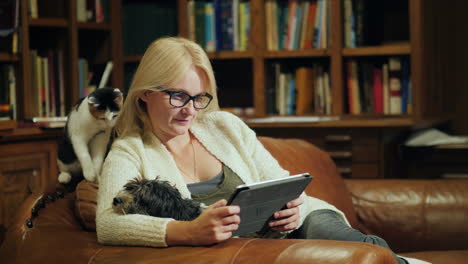 a woman reads a book in a tablet sits in the luxurious back of the library