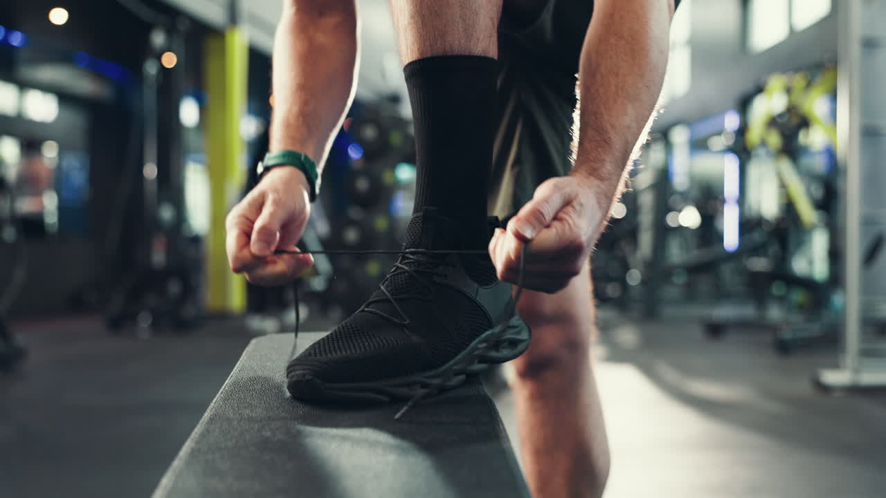 Uomo che si allaccia le scarpe da ginnastica in palestra