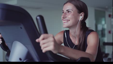 exercise bike cardio workout at fitness gym of woman taking weight loss. female listens to music on headphones. athlete builder muscles lifestyle