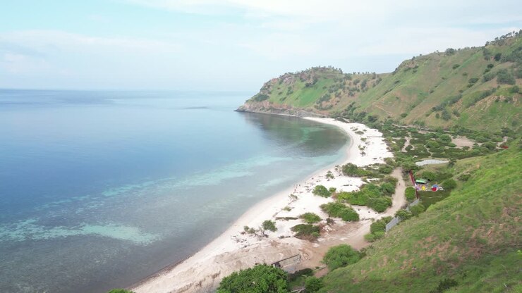 A peaceful coastline in dili timor leste with green hills and calm waters, aerial view