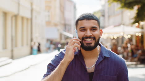 happy man guy having remote conversation talking on smartphone good news gossip in city street