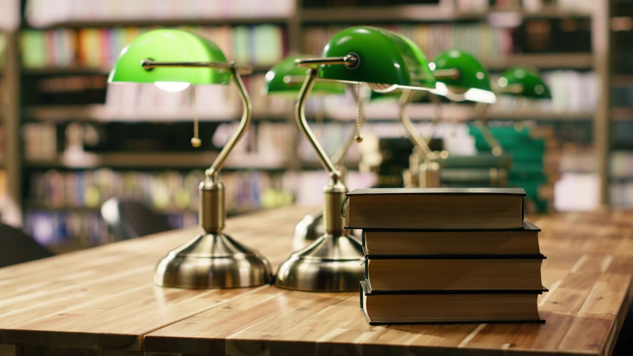 Stapel Hardcover-Bücher auf einem hölzernen Schreibtisch in einer leeren Bibliothek.