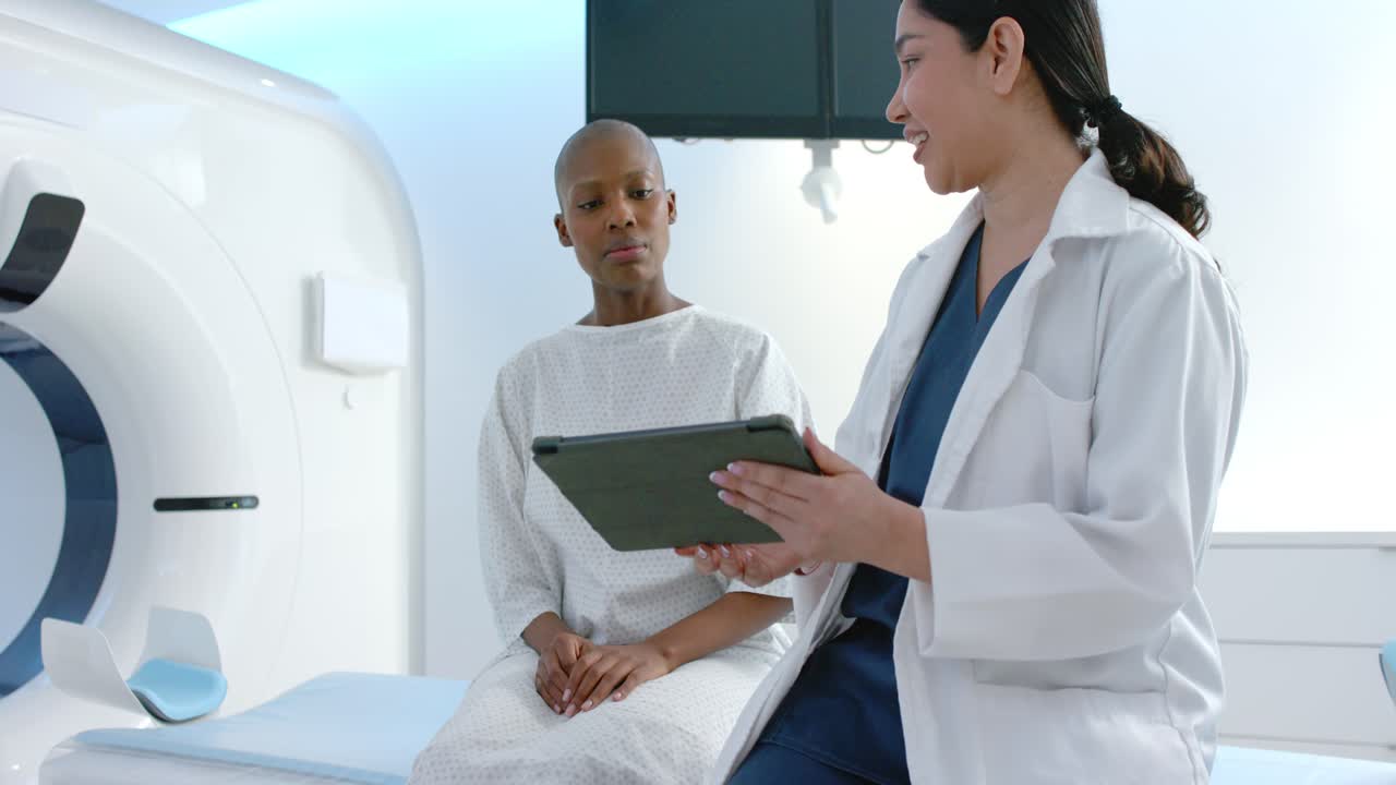 Un medico che consulta una scansione su tablet mentre una paziente in camice ascolta in una sala d'esame vicino al portale della TAC