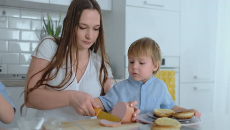 La-Joven-Madre-Ayuda-A-Un-Niño-A-Cocinar-Hamburguesas-En-La-Cocina.