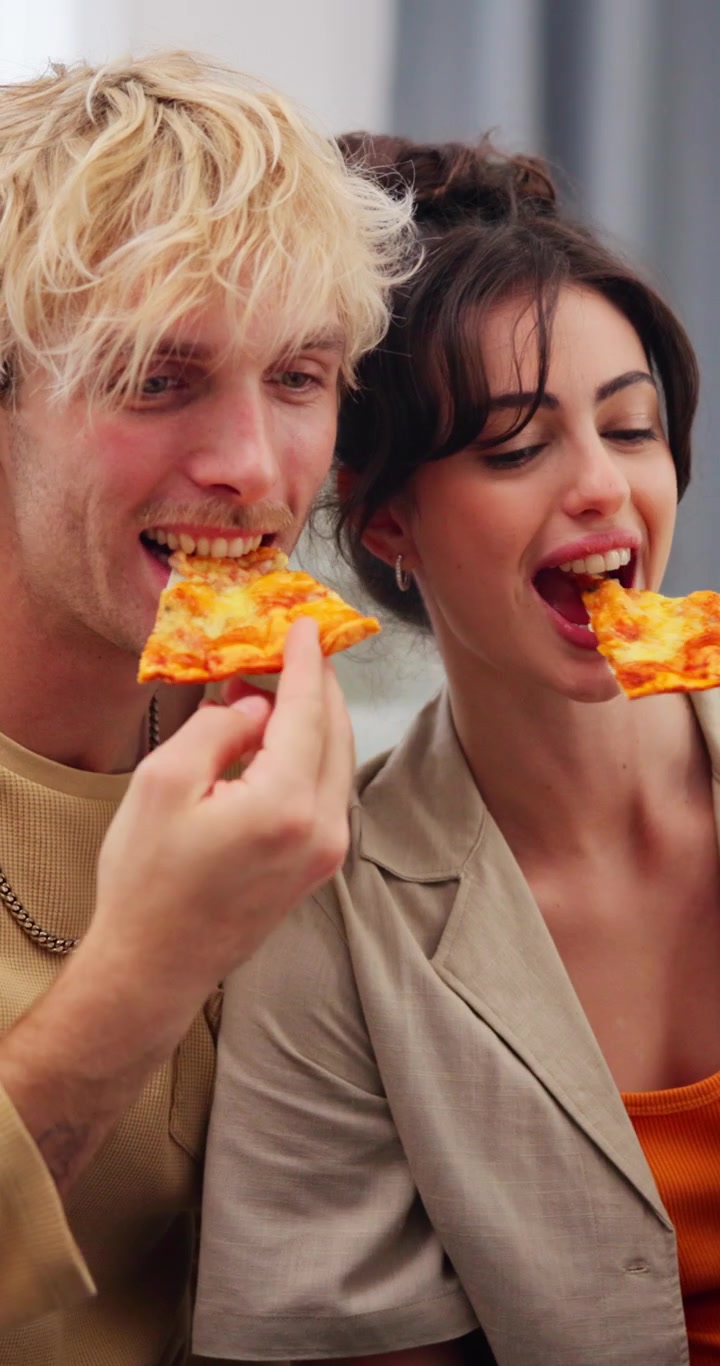 Giovane coppia che mangia la pizza insieme nel nuovo appartamento