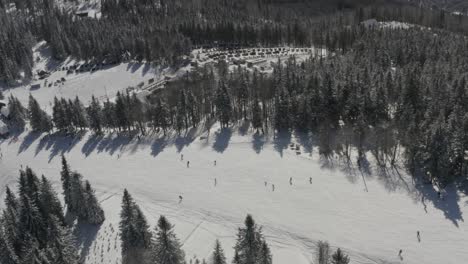 ribnica track at kope ski resort slovenia with skiers going downhill, aerial pan left reveal shot