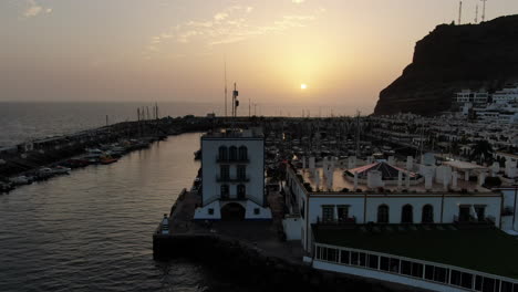 Puerto-De-Mogan:-Vista-Aérea-Con-Movimiento-De-Grúa-Y-Durante-La-Puesta-De-Sol-De-La-Ciudad-De-Puerto-De-Mogan-Con-Hermosos-Colores