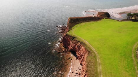 Antenne-über-Offene-Grüne-Landschaft-Mit-Küstenstrand-Von-Devon-Im-Hintergrund