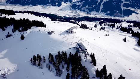 Vista-Aérea-De-La-Estación-De-Esquí-Con-Gente-Haciendo-Snowboard-Cuesta-Abajo