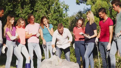 Mid-adults-volunteering-and-man-taking-notes-during-river-clean-up-day