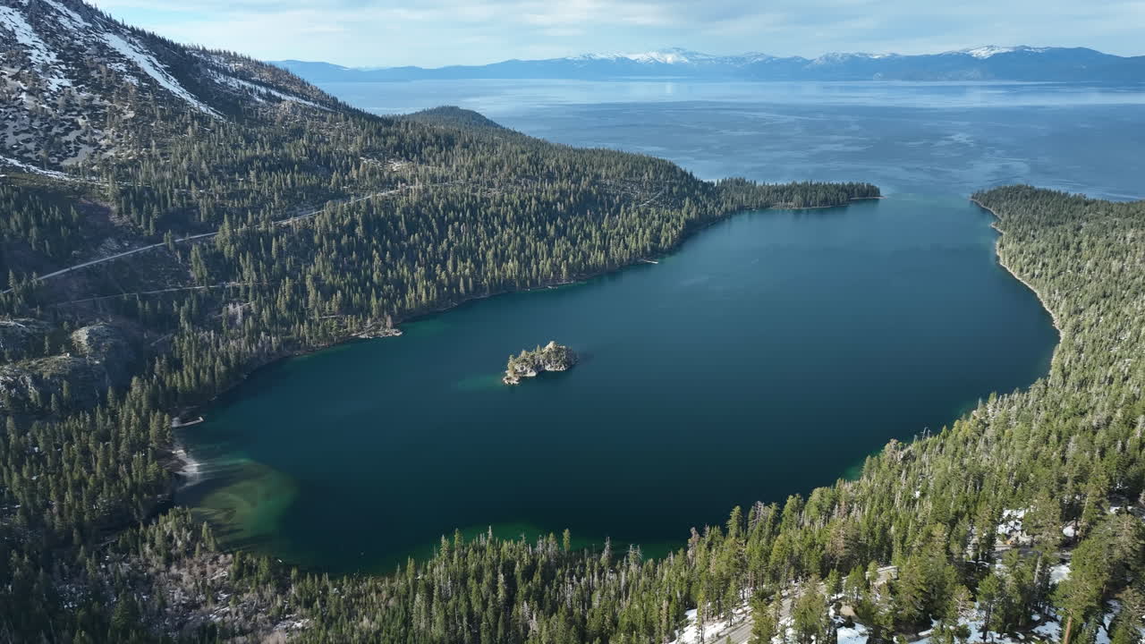 Establishing drone shot of the snowy Emerald bay, sunny spring day in Tahoe, USA