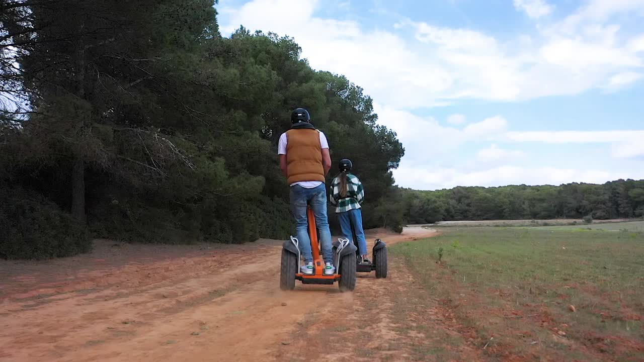 los turistas montan un scooter segway a través del bosque y los campos