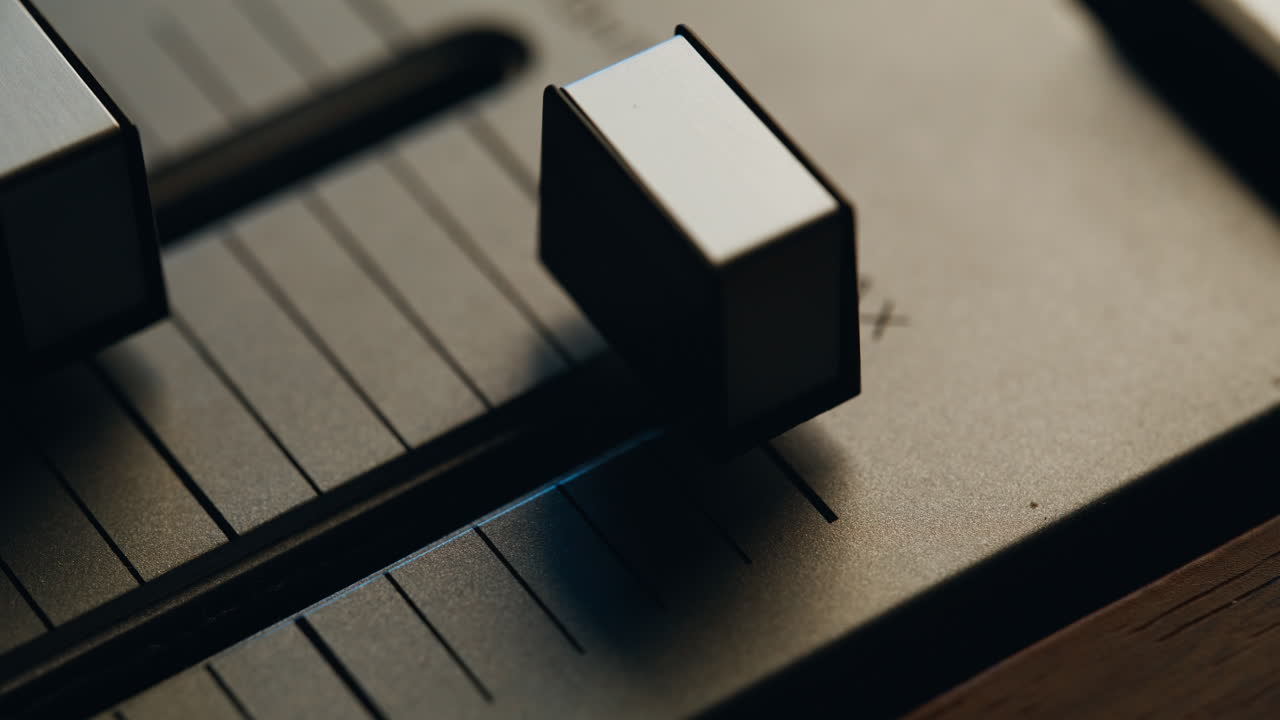 Finger pushing volume slider on vintage audio mixer device closeup macro view