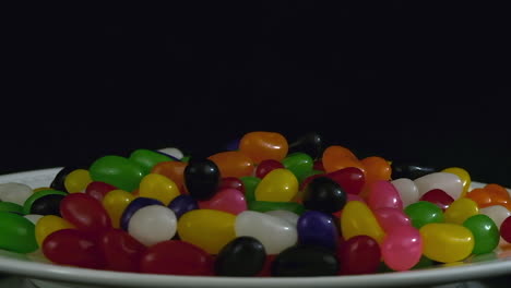 narrow focus plate of colorful jelly beans revolve on black background