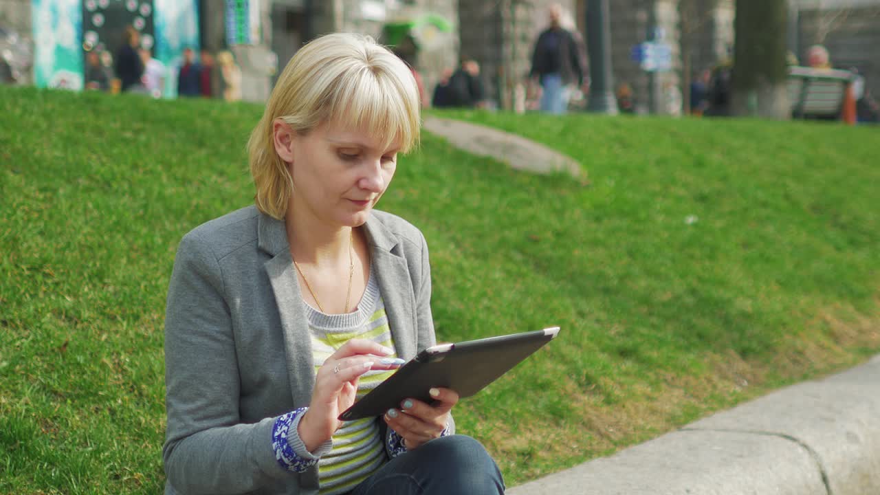 공원에서 쉬고 있는 젊은 여성은 디지털 태블릿 4k 비디오를 즐긴다