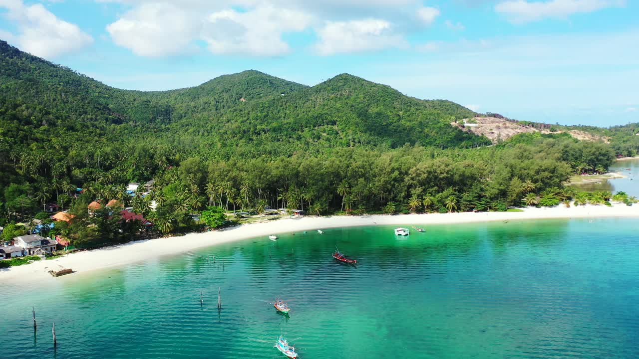 Barcos flotando en las tranquilas y cristalinas aguas de una laguna turquesa cerca de una playa de arena blanca en una isla tropical con abundante vegetación en Tailandia