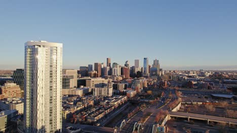 Drone-Aerial-View-Of-Denver-Colorado-Downtown-Skyline-Flying-Past-High-Rise-Apartment-Complex-During-Golden-Hour-Sunset