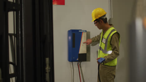 Asian-male-worker-wearing-safety-suit-with-helmet-in-warehouse