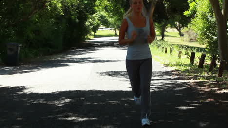 A-woman-jogs-down-a-road-with-the-camera-in-front-of-her-pulling-away