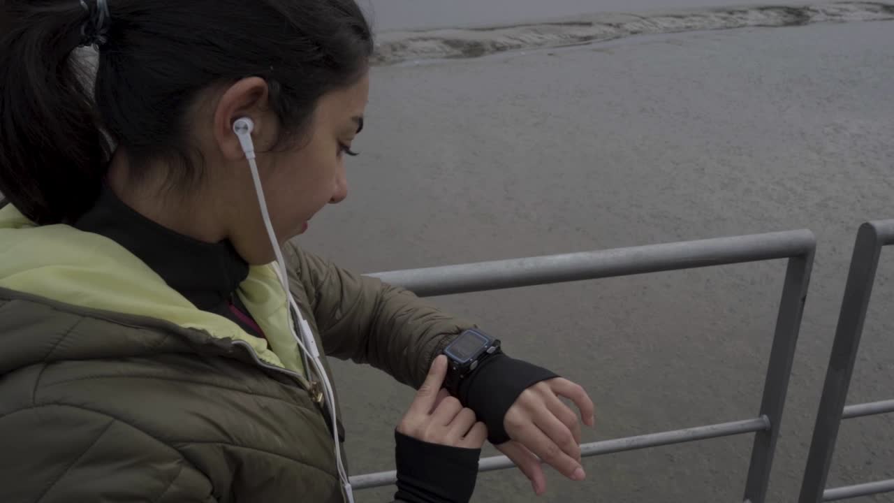 disparo en cámara lenta de una joven bruneta deportiva poniendo un reloj deportivo