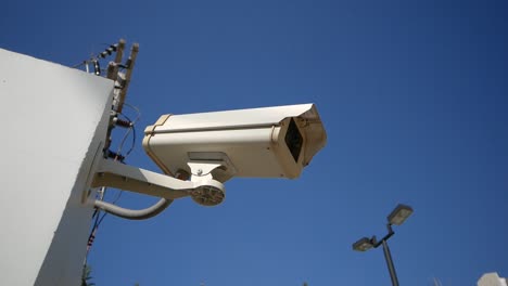 close-up white surveillance camera with blue sky in background