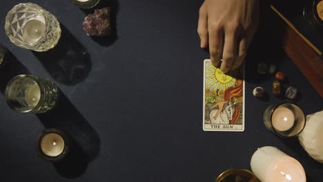 overhead shot of person giving tarot card reading laying down the sun card on table 1