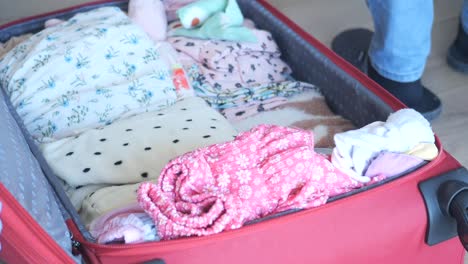 red suitcase packed with baby clothes and accessories