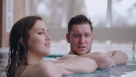 adult man and woman are lying in swimming pool relaxing and chatting cheerfully wellness center