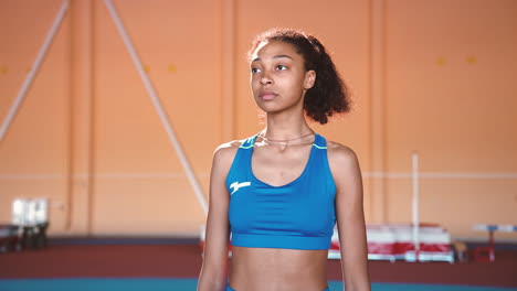 zoom in camera shot of a focused young sportswoman standing in an indoor sport facility and looking at camera