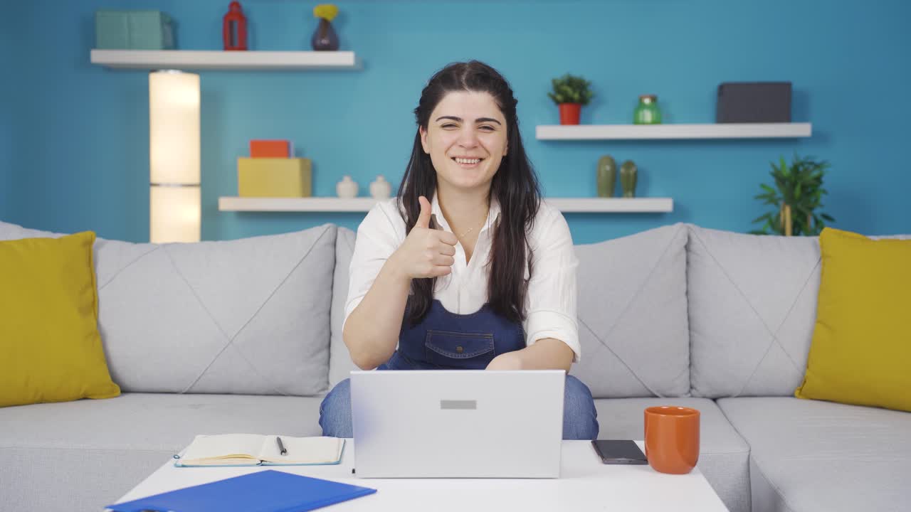 mujer mirando la computadora portátil haciendo un gesto positivo.