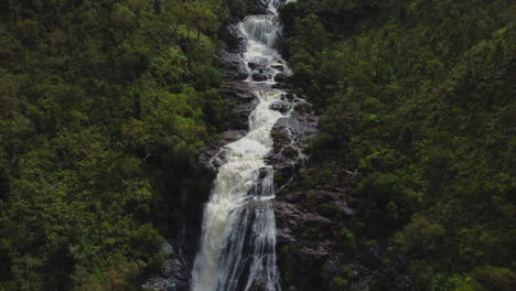 Aerial-zoom-out-from-majestic-Colnett-waterfall-near-Hienghene,-revealing-landscape-over-the-east-coast-of-New-Caledonia