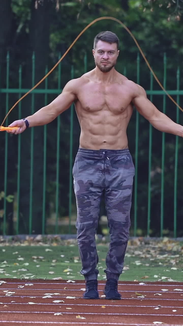 Uomo in forma che salta la corda allo stadio. Atleta maschio esegue l'esercizio di salto con la corda allo stadio.