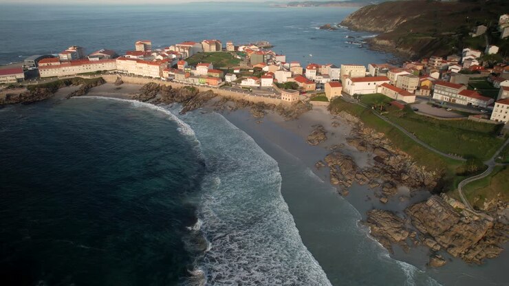 Vista aerea delle onde dell'oceano sulla spiaggia e delle case residenziali a Caion, La Coruña, Spagna