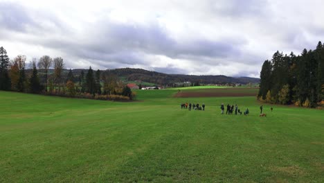 gathering of people in a green meadow in bavaria germany on an autumn morning with a village in the background