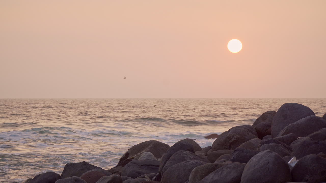 페루 리마 산바르톨로 해안을 따라 있는 바위 해변에서 정적 일몰이 촬영되었습니다.
