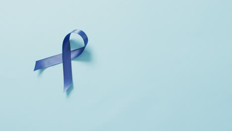 video of dark blue colon cancer ribbon on pale blue background