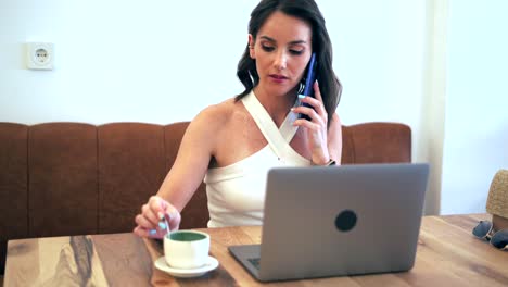 Businesswoman-talking-on-smartphone-and-browsing-laptop-during-work