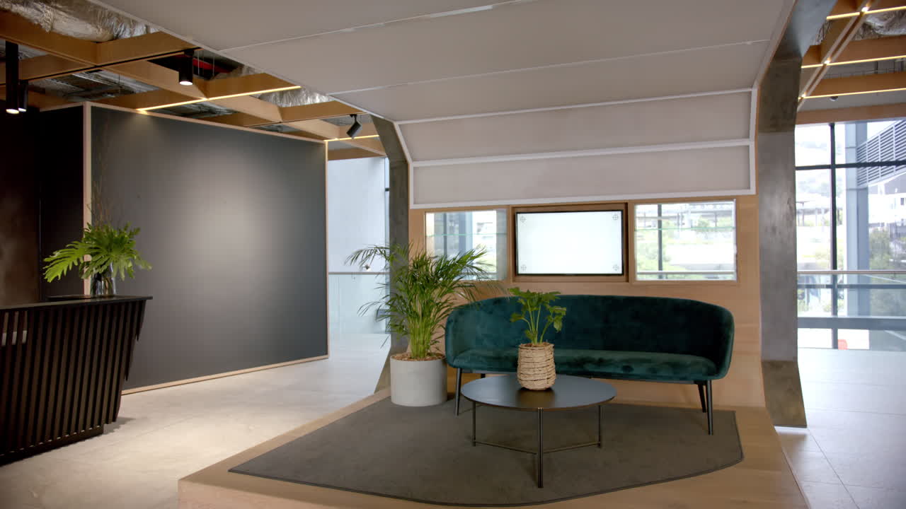 Modern office lobby with green sofa, coffee table, and indoor plants, copy space
