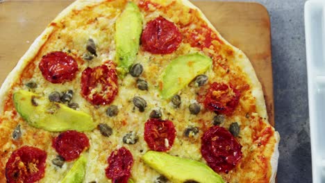 baked pizza with avocado, cherry tomato and olive toppings