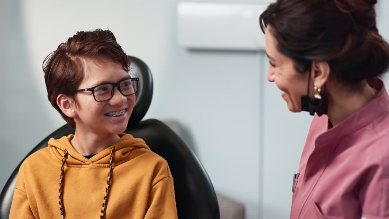 un niño sonríe felizmente al dentista mientras le revisan los aparatos dentales